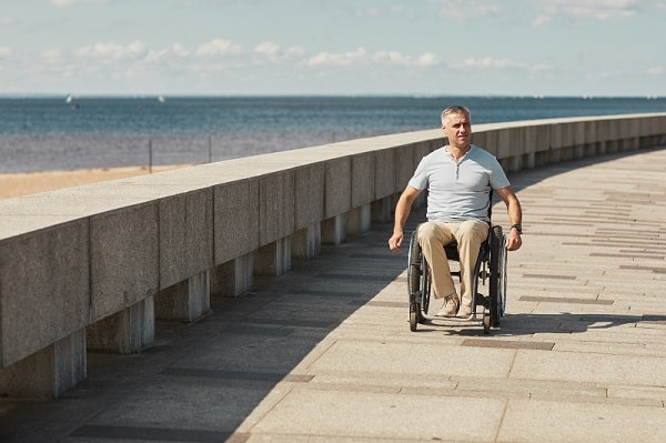 A man on a seaside holiday enjoys riding along the promenade, safe in the knowledge his chair is protected with wheelchair travel insurance 