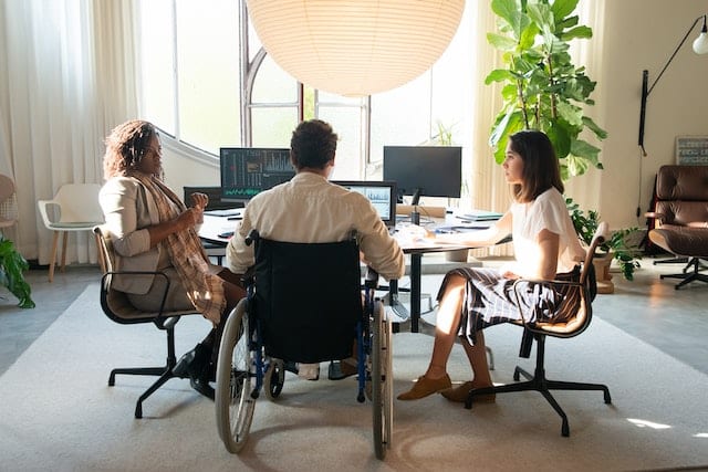 Three colleagues in a home office look at the role descriptions for a few jobs for people with disability they will need to staff their growing start-up. 