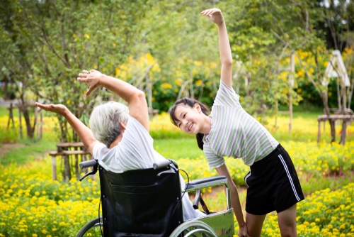 A girl does stretches with her gran who has limited lower limb mobility, to help her stay active and fit