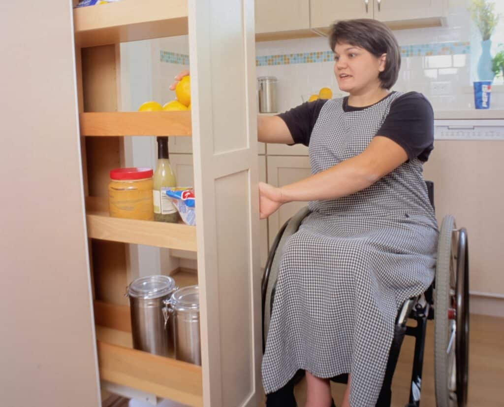 A woman in a wheelchair unpacks supplies from the cupboard to put inside her family's bushfire survival kit