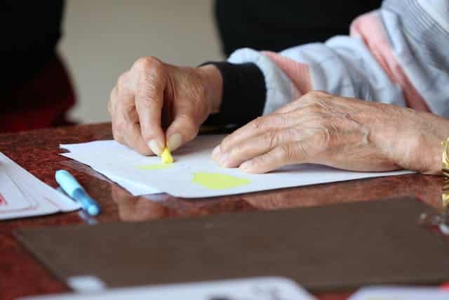 An elderly woman in Australia is writing on a piece of paper.