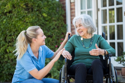 A nurse providing care and support to an elderly woman in a wheelchair, focusing on preventative measures for pressure sores