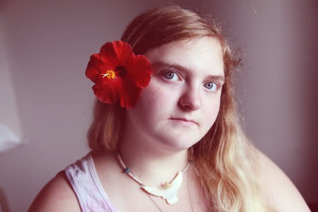 A girl with a red flower in her hair, celebrates what neurodiversity is 