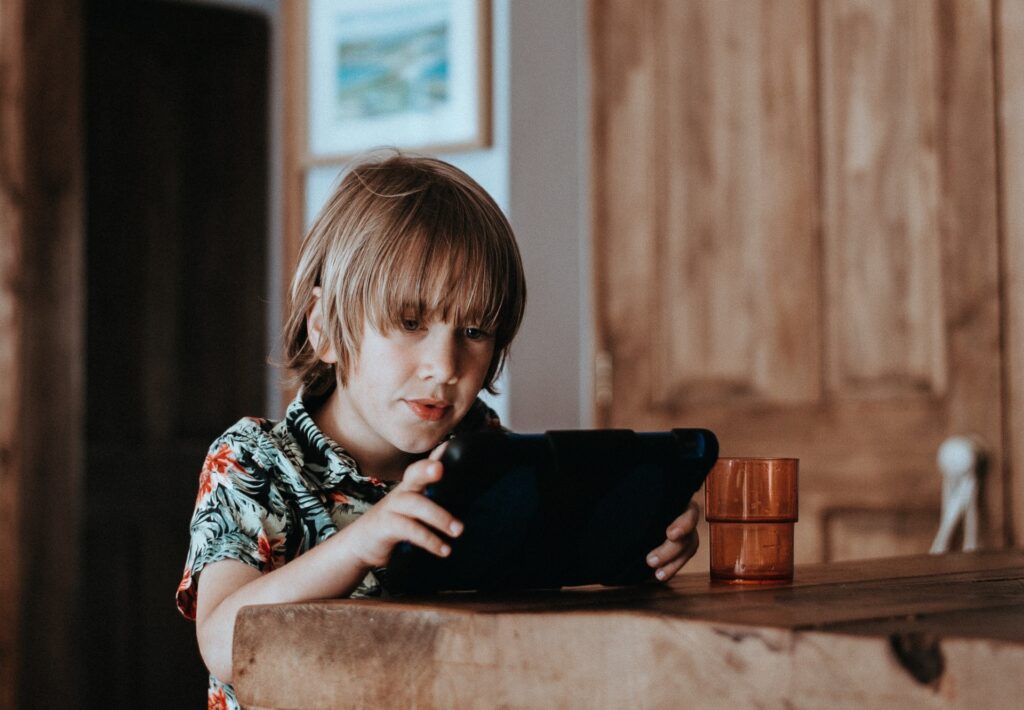 A young boy who is  neurodivergent learns with a tablet in a one on one environment to cater to his individual learning needs