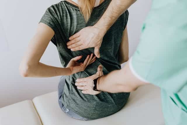 Woman undergoing treatment with a doctor examining her back.