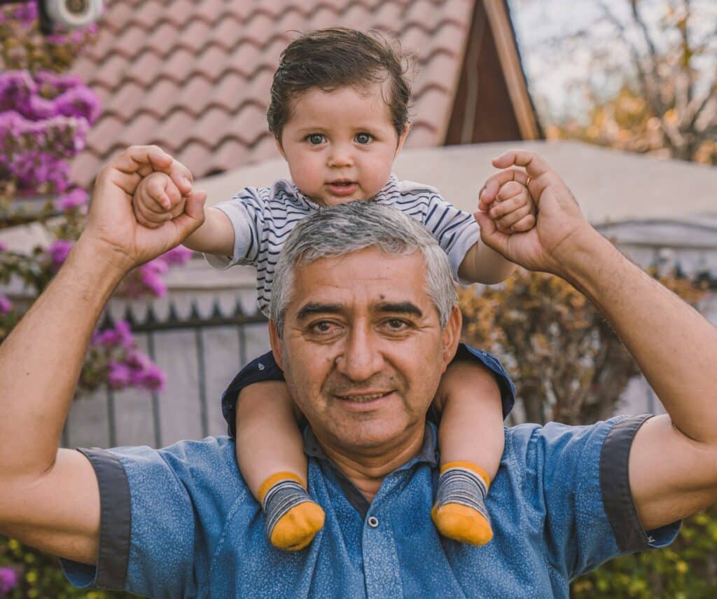 A carer holding a baby on his shoulders.