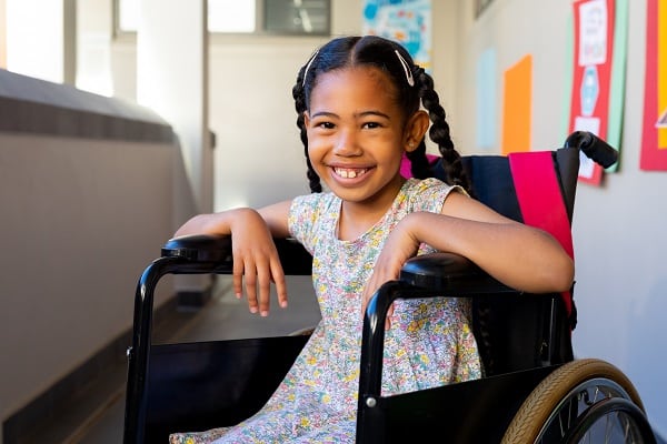 A young girl in a wheelchair smiling at the Disability Expo.