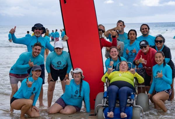 Volunteers from the Disabled Surfers Association of Australia enjoy a photo opportunity with a surfer who has just been enjoying learning to surf with limited mobility