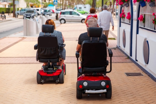 a couple take their electric mobility scooters for a ride around town.