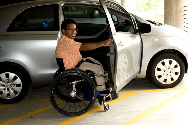 middle aged man accessible side of car in wheelchair from accessible disability parking space in car park