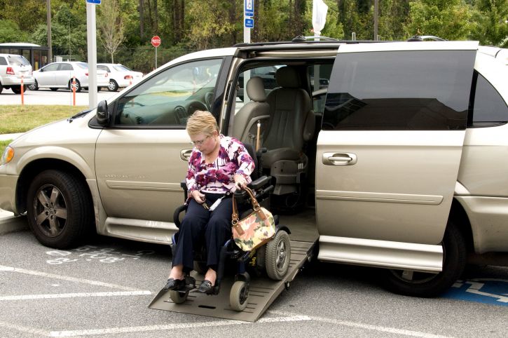 elderly lady going down wheelchair ramp in disability parking spot outside in wheelchair accessible vehicle