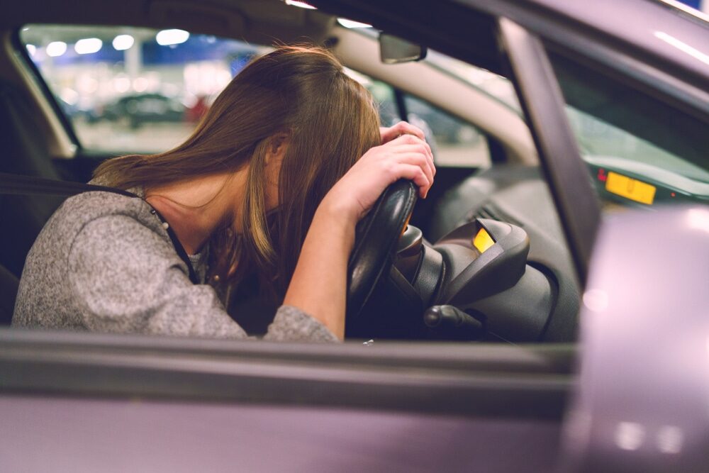 woman with painful Invisible disabilities sits in her car after parking as symptoms take hold