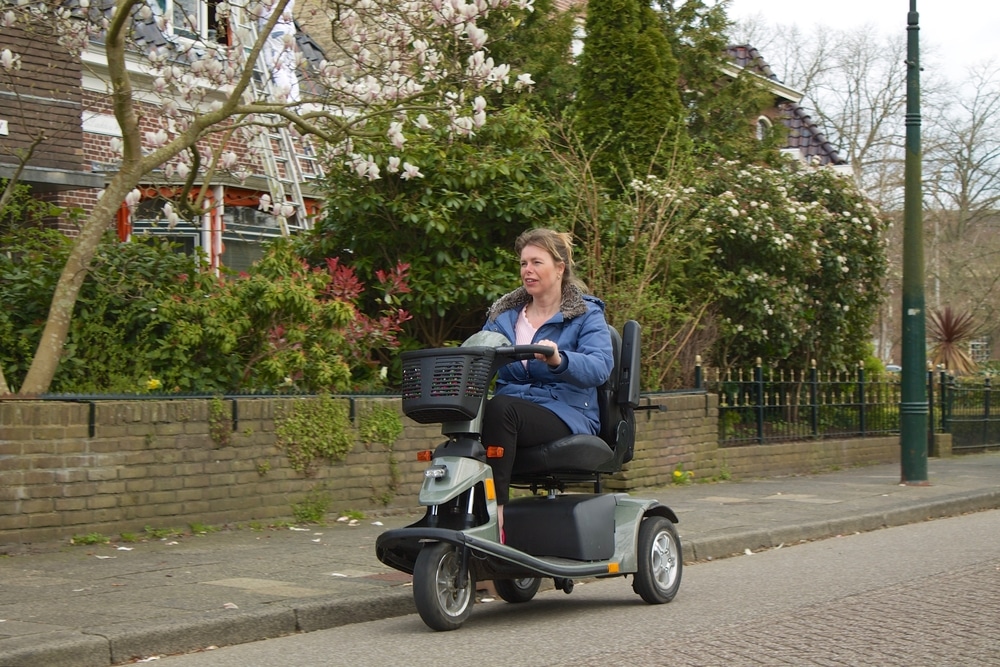 Woman operating a mobility scooter on a suburban street, safe in the knowledge she recently signed up for insurance for mobility scooters.