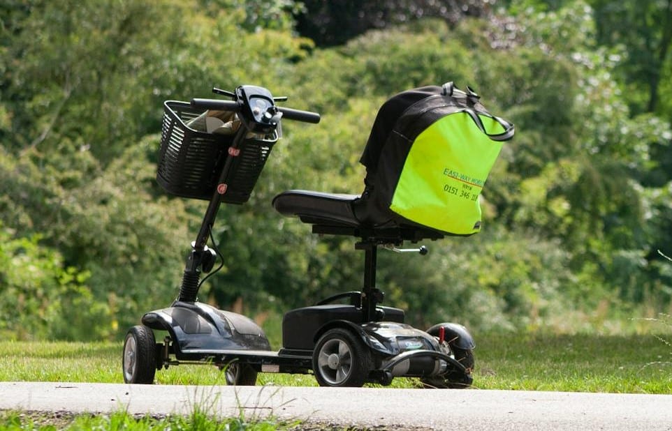 Electric mobility scooter parked on a pathway with a high visibility jacket draped over the seat.
