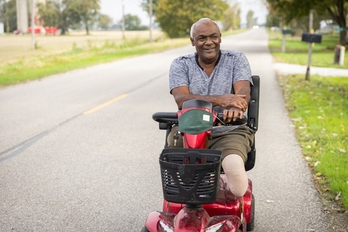 A man rides through along a small road alongside a park in Perth on his scooter