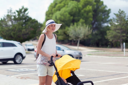 Young mother pushing in parking lot with pram