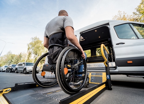 A man in a wheelchair moves to the lift of a specialised vehicle