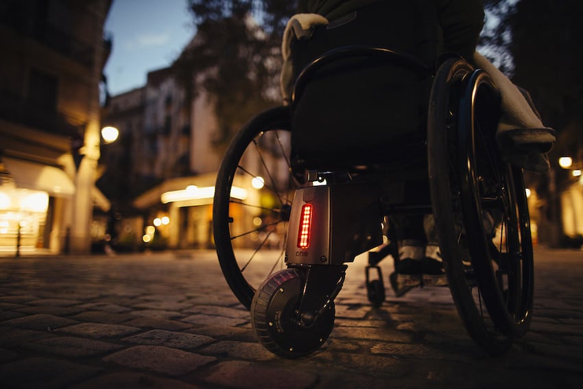 This wheelchair on a cobblestone street at night with a lit-up cafe in the distance is about to do a wheelchair to car transfer