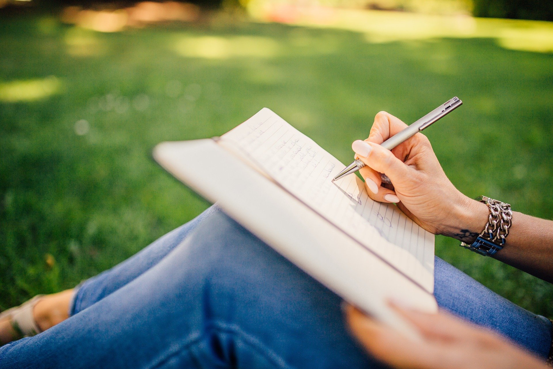 Girl sitting outside writing in notebook