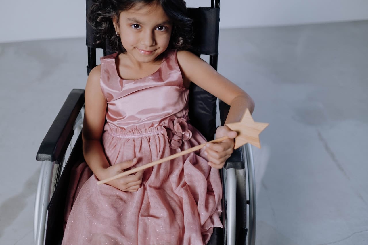 Children's wheelchairs are vital to their mobility. This photo shows a little girl in a pink dress on a kids wheelchair