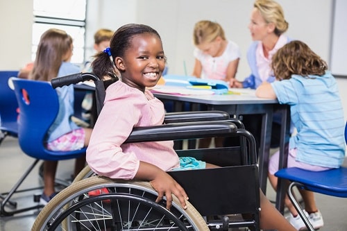 Childrens wheelchairs are vital to their independence This photo shows a schoolgirl in a wheelchair smiling in a school classroom. 