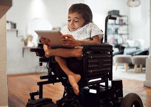 A little boy with physical disabilities at home watching kids' shows on a tablet