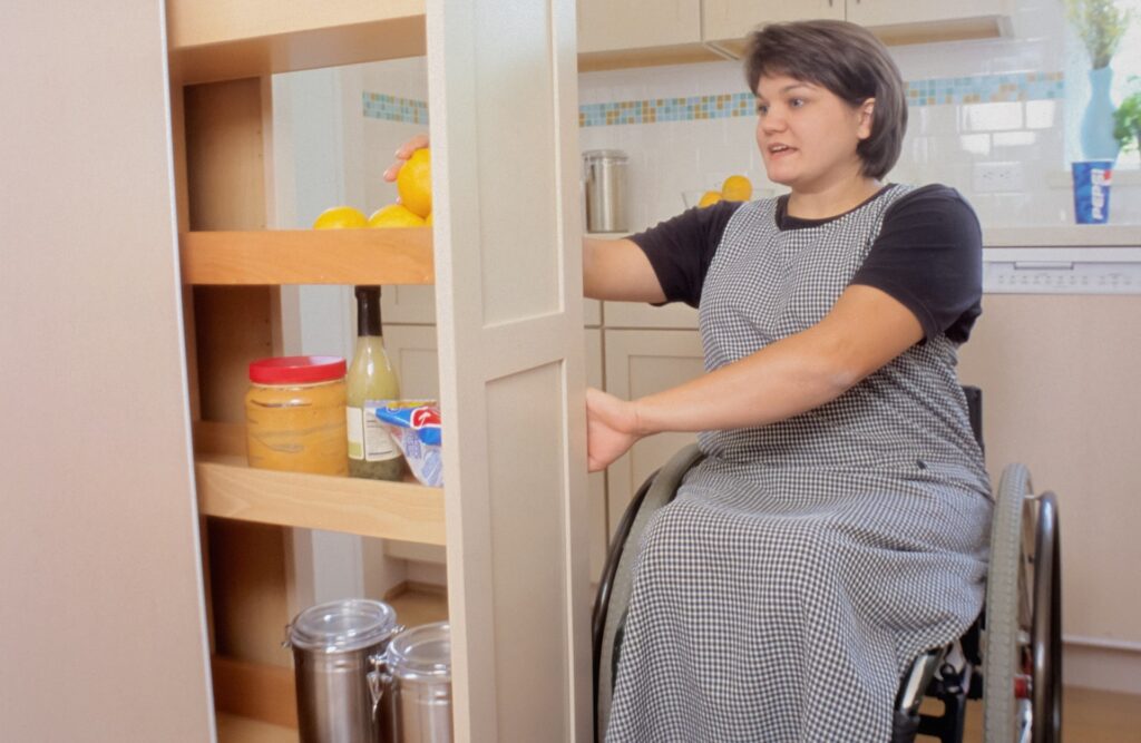 Woman easily navigates her accessible home with built-in slide-out kitchen cupboards for ease of use