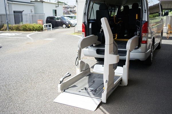 A van equipped with a wheelchair lift, perfect for those comparing disability car insurance options, is parked with the lift extended to the ground, ready for use.