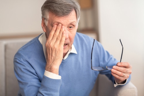 tired elderly man rubbing eye due to glaucoma