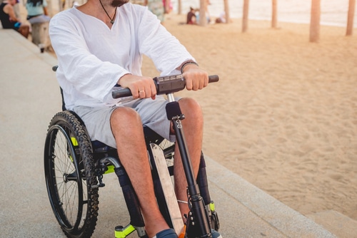 blue badge insurance for mobility scooters might cover this man riding a mobility scooter near the beach