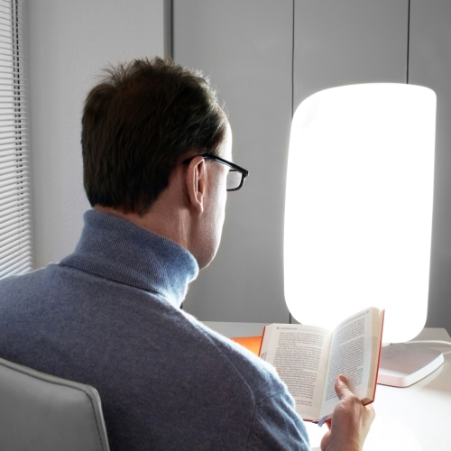 man in front of light therapy lamp which is a gadget which can help with mood