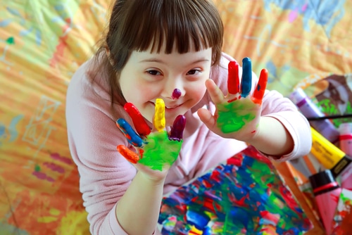 arts and crafts can make good presents for children with disabilities. This little girl with Down Syndrome is playing with paint on her hands