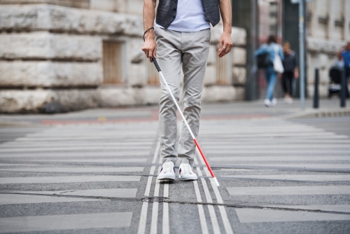 young blind man walking with cane on street