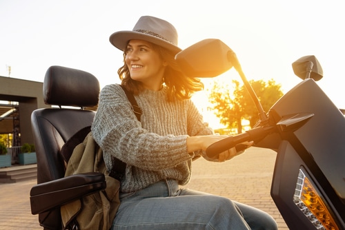 young woman using mobility scooter at sunset