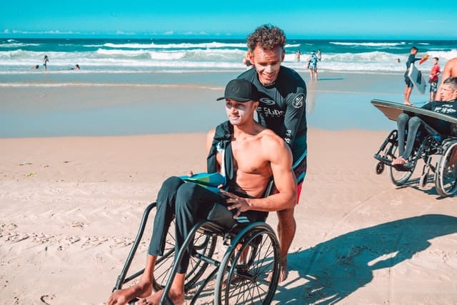 man on beach in wheelchair. Some beaches in australia offer wheelchair hire