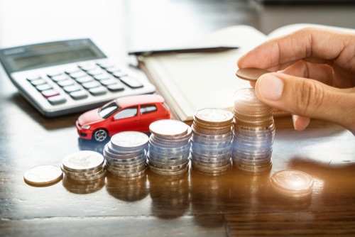 A hand stacking coins on a desk. Blue Badge Insurance offers pet insurance for cats.