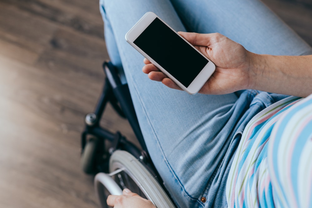 women in wheelchair uses accessibility features on smartphone