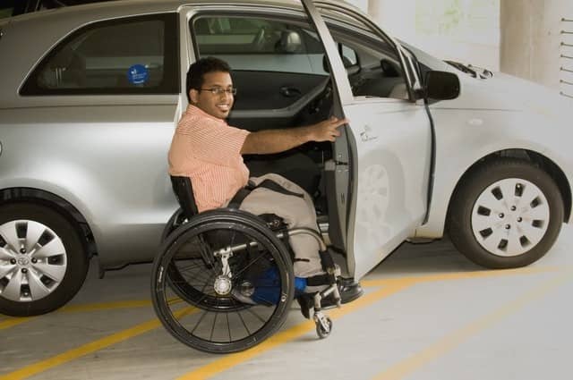 A man in a wheelchair in front a WAV. You should avoid driving without insurance because getting into a car accident with no insurance can lead to a hefty financial burden on you.