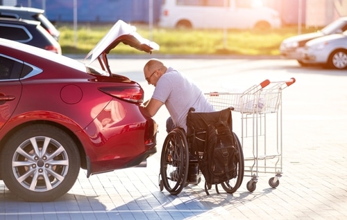 man in wheelchair using disability parking to load boot