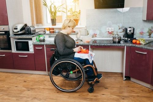 woman in wheelchair chopping salad - an occupational therapy assessment will cover areas such as food prep