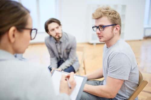 This blonde man wearing glasses is speaking with doctors about his brain fog