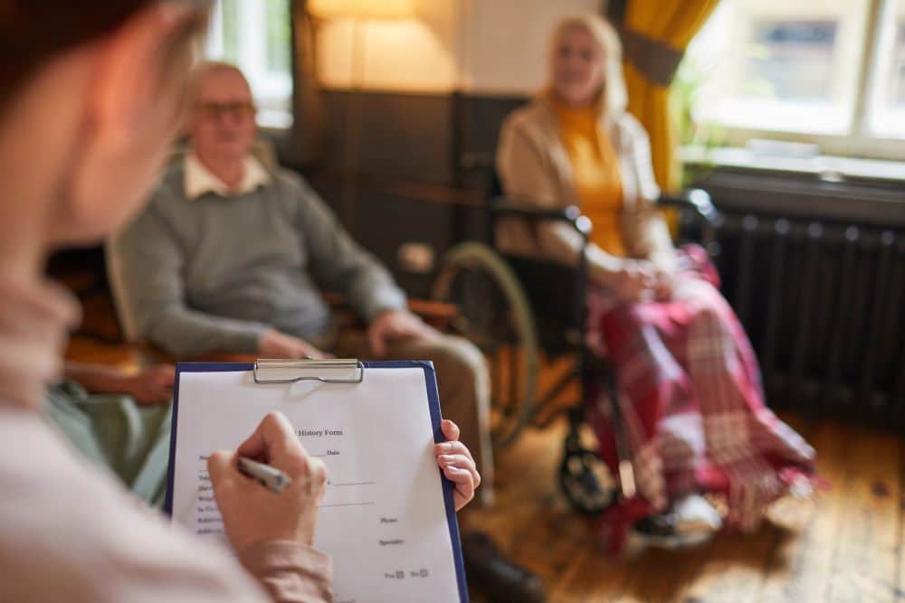 An occupational therapist collects data from a couple in wheelchairs. They may be wondering will the NDIS fund my wheelchair?