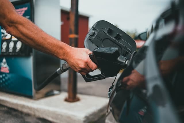 a male hand pouring petrol into a car to save fuel