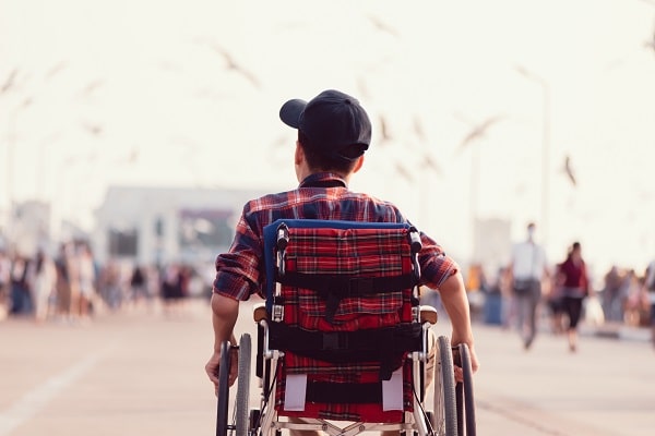 child in flannel shirt facing away in wheelchair has benefited from wheelchair hire
