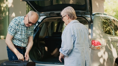 senior couple in seniors parking spot loading luggage into boot