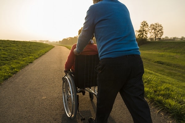 An elderly man with dementia pushing his wife in a wheelchair after choosing a wheelchair