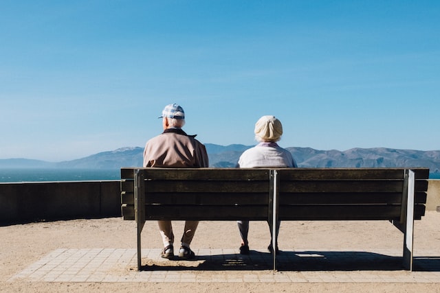 This older man and woman sitting on a bench looking out to sea discuss one difference with Alzheimer's vs dementia is 2/3 of dementia cases in Australia are women