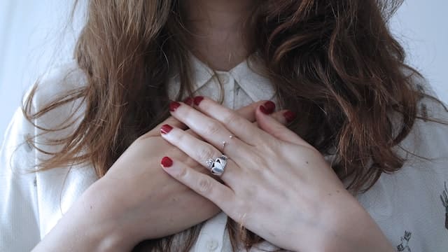 woman clutches her hands to her heart for Red Feb