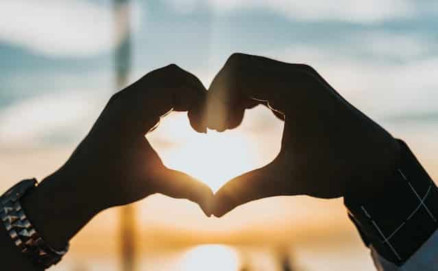 two people form a heart with their hands to honour Heart Research Month and random acts of kindness day