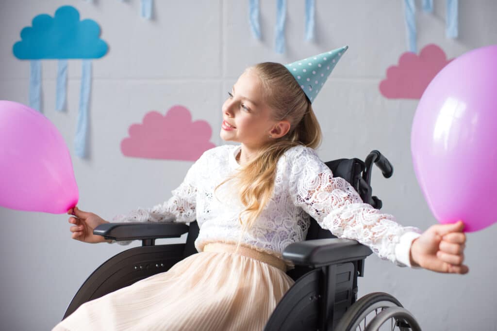 a birthday girl celebrates while sitting in a wheelchair which her parents have made the most comfortable they can